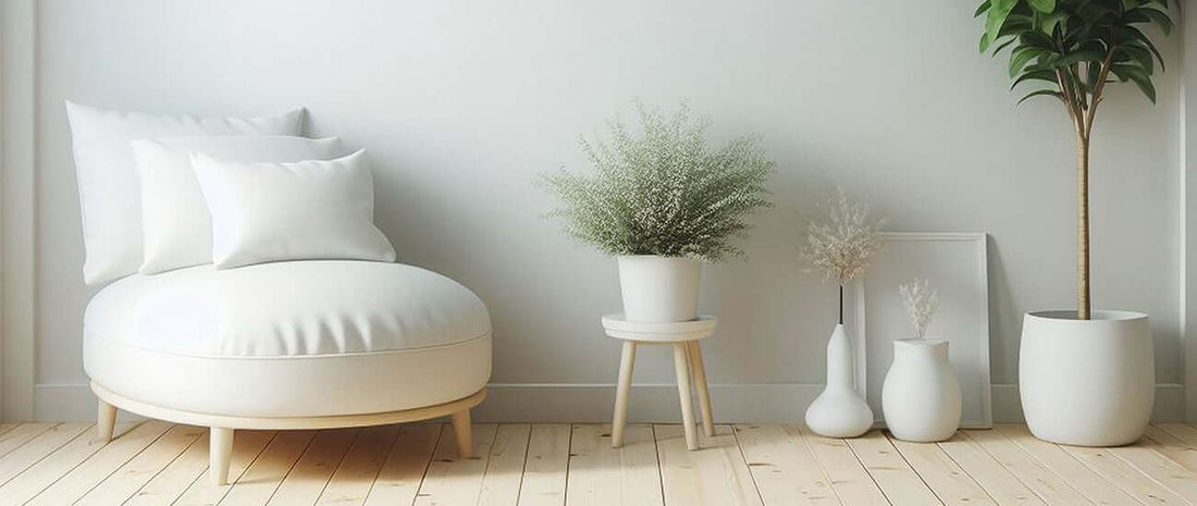 Cozy minimalist living space with a white lounge chair, decorative plants, and light wooden flooring for a serene atmosphere.