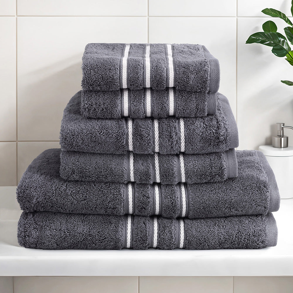 Luxury grey cotton bath towel set stacked on a bathroom countertop, featuring plush texture and elegant design.