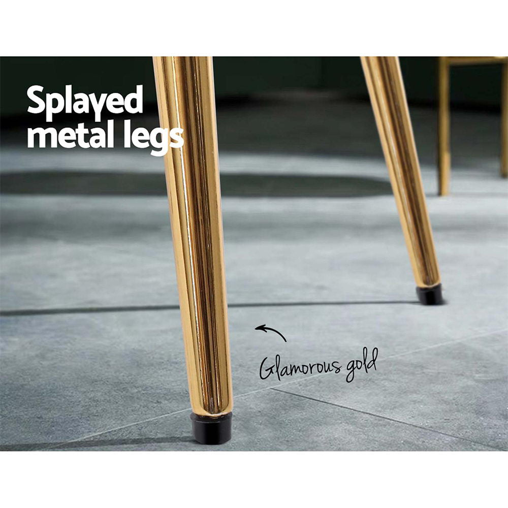 Splayed metal legs of a chair in glamorous gold finish, showcasing elegant design and modern aesthetics.