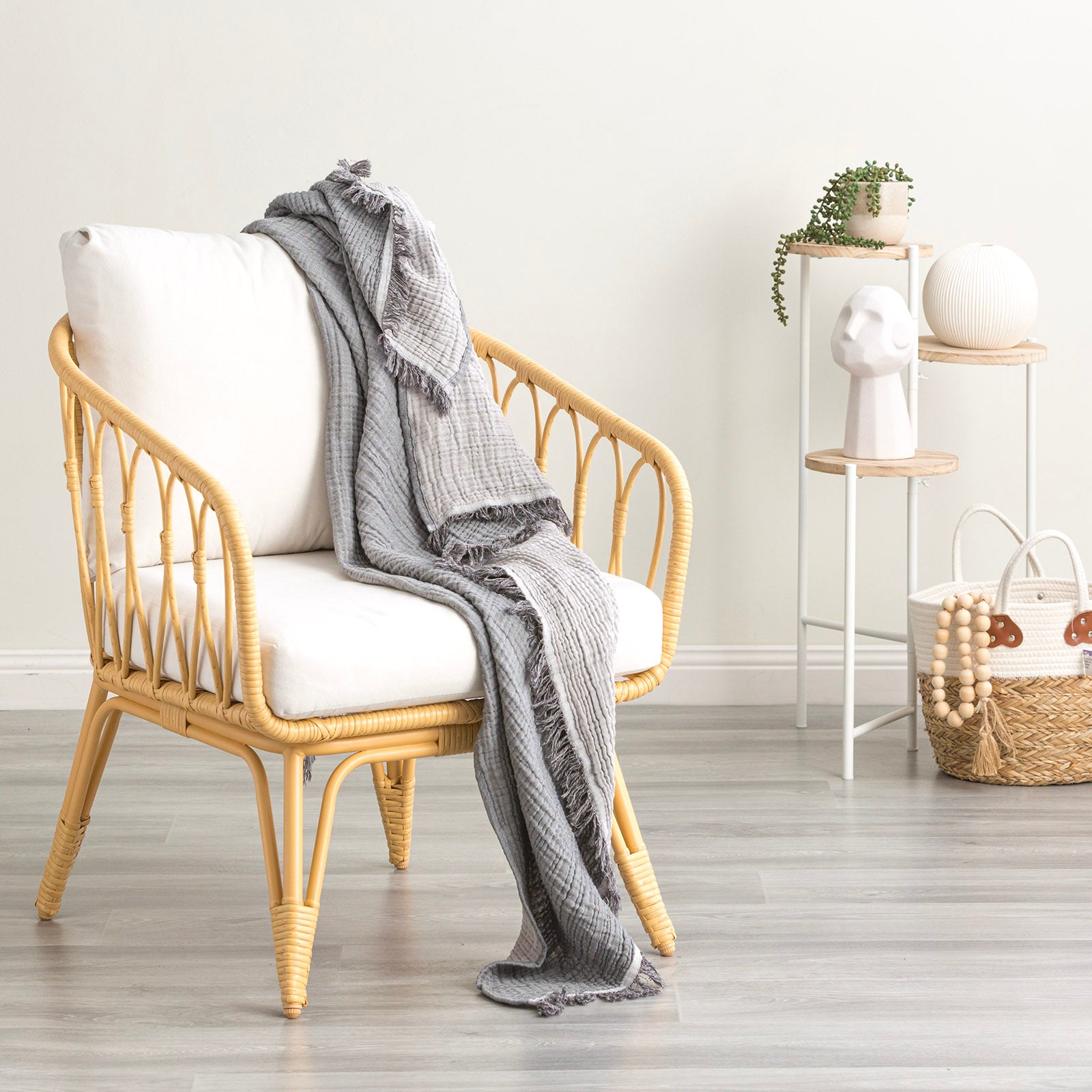 Cozy vintage washed cotton throw draped over a stylish rattan chair in a bright, modern living space.