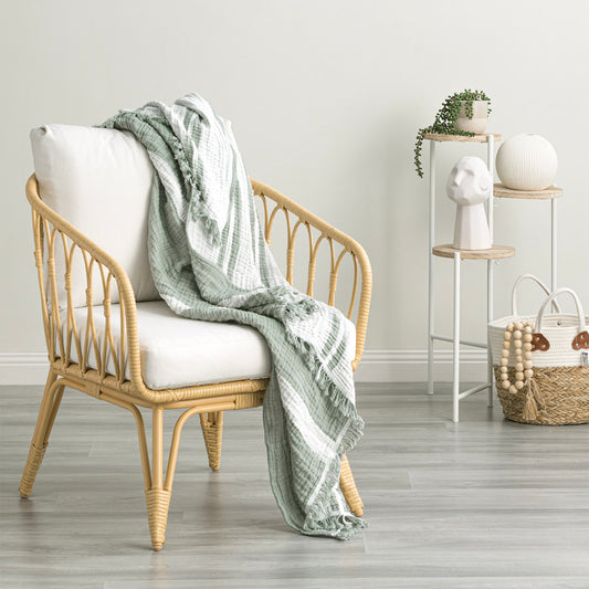 Ray Striped vintage washed cotton throw draped over a stylish rattan chair in a modern living space.