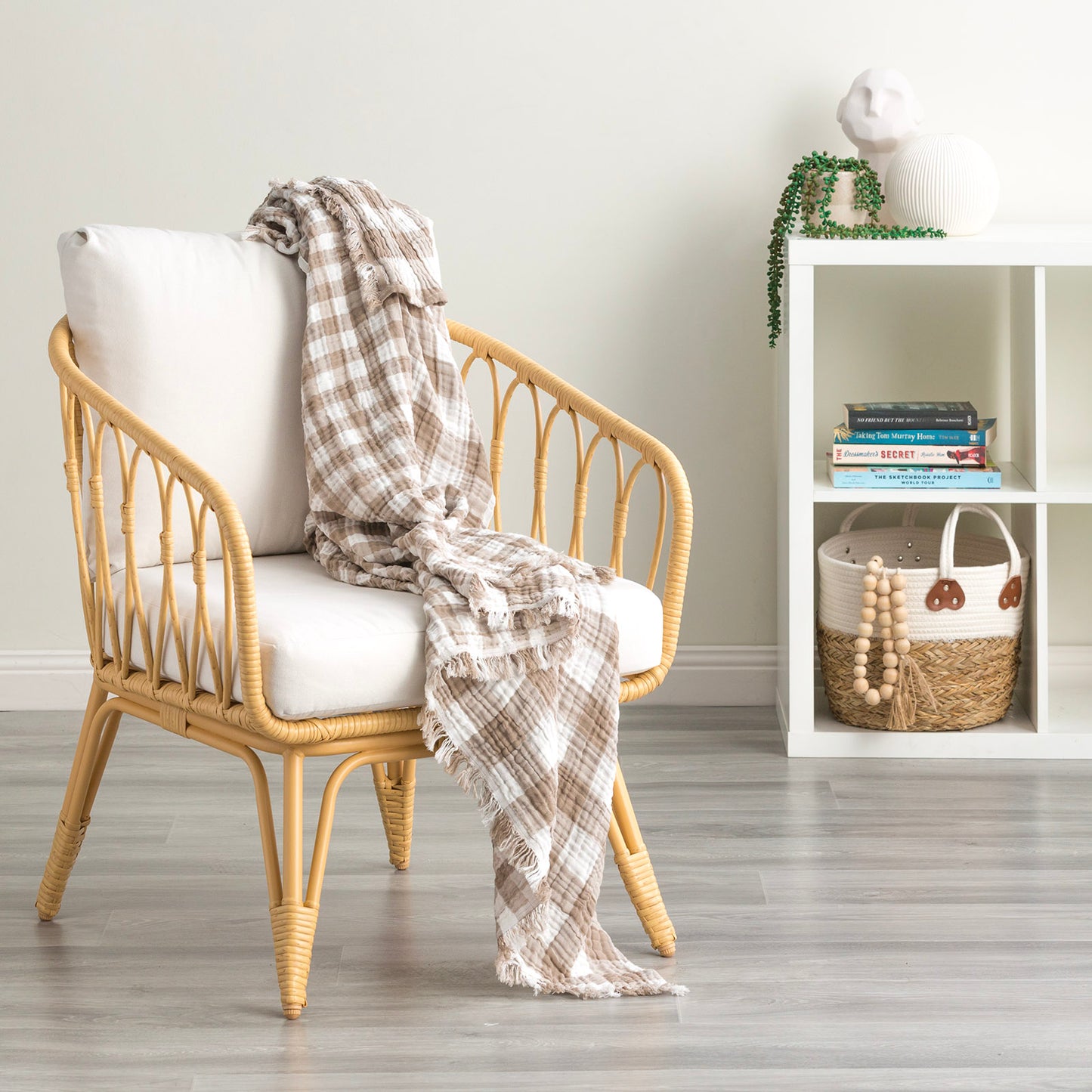 Cozy Atlantic reversible cotton throw blanket draped over a stylish rattan chair in a bright, modern living space.