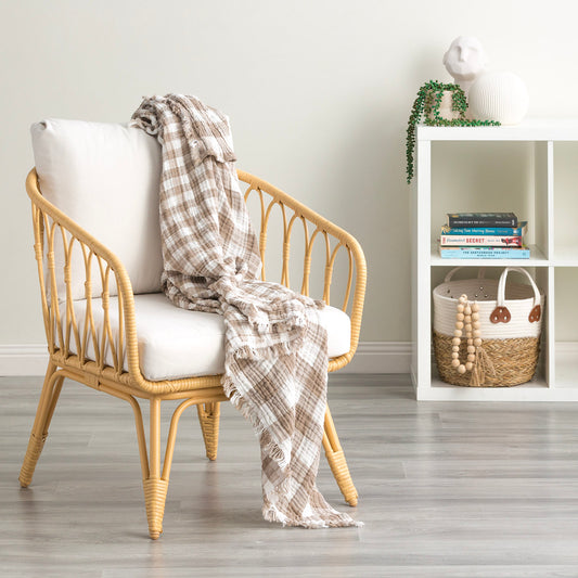 Cozy Atlantic reversible cotton throw blanket draped over a stylish rattan chair in a bright, modern living space.