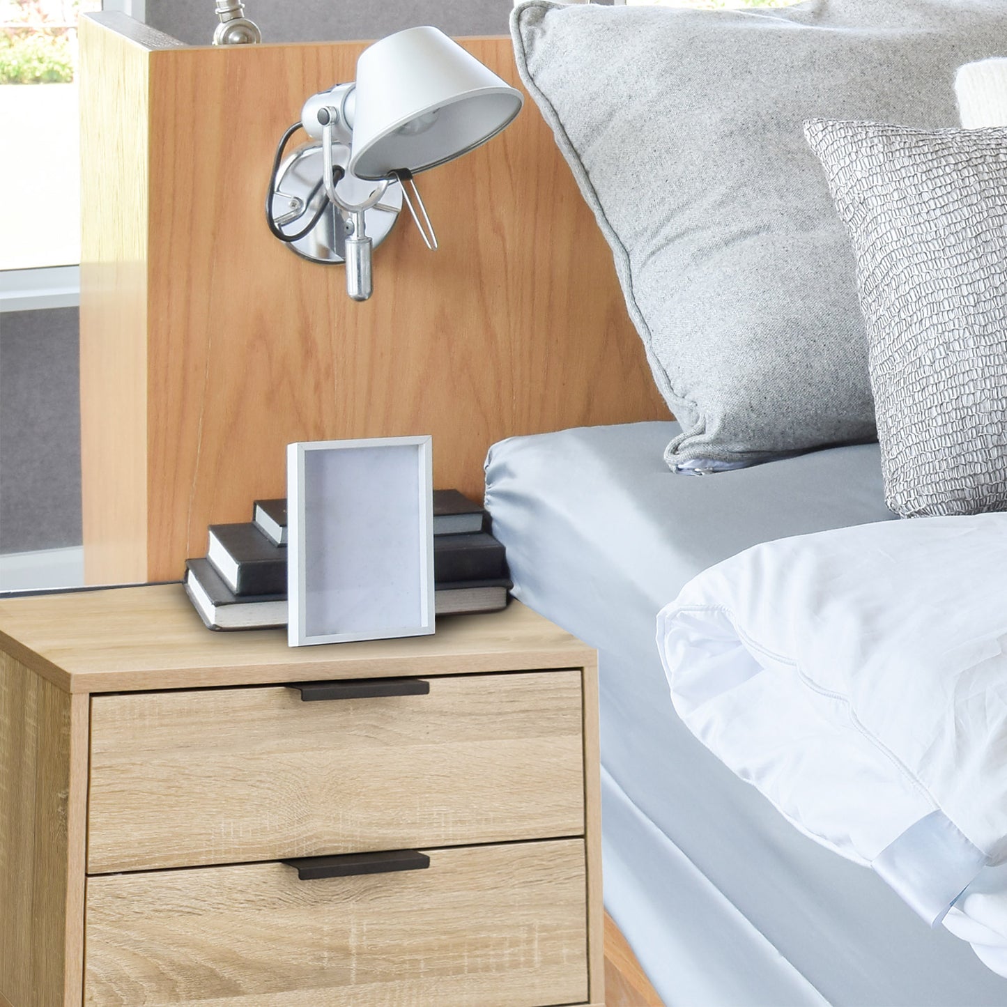 Modern wooden Milano Decor bedside table with two drawers, featuring a sleek design next to a cozy bed, ideal for bedroom storage.