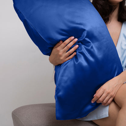 Luxurious navy blue satin pillowcase held by a woman, showcasing smooth fabric perfect for bedding comfort.