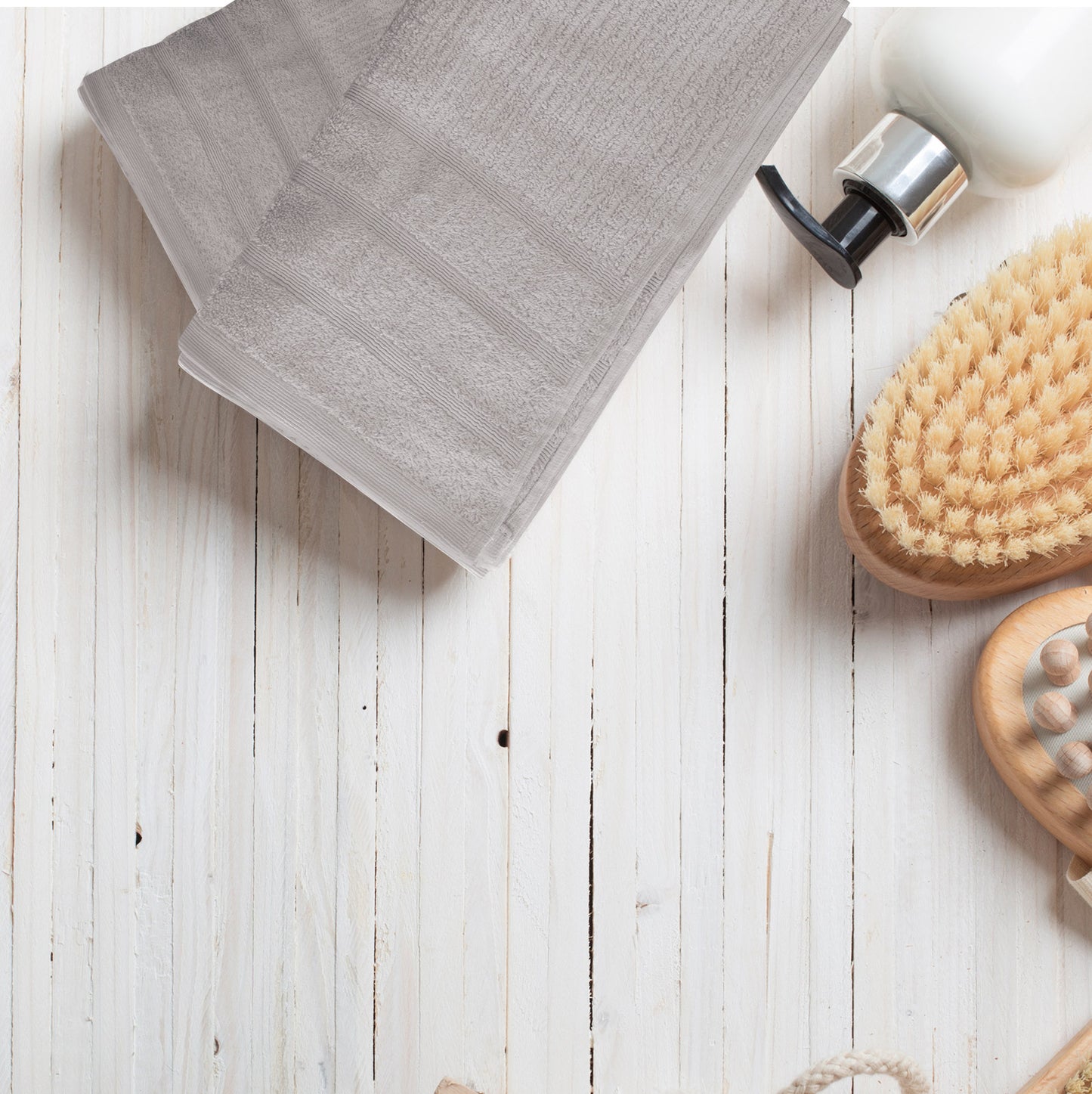 Luxury grey Egyptian cotton bath towels set on rustic wood background with bathroom accessories.