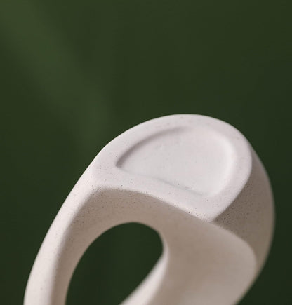 Close-up of a creative white ceramic vase showcasing minimalist design with smooth curves and a textured surface.