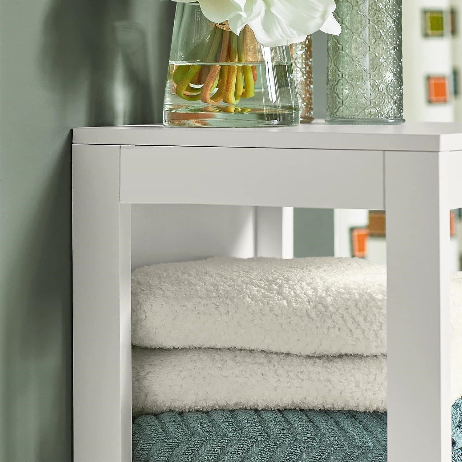 Freestanding white cabinet with towels and decor, perfect for stylish storage and organization.