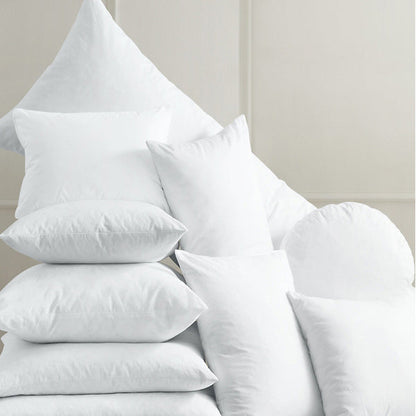 A variety of white cushion inserts stacked in different shapes and sizes, ideal for enhancing any home decor.