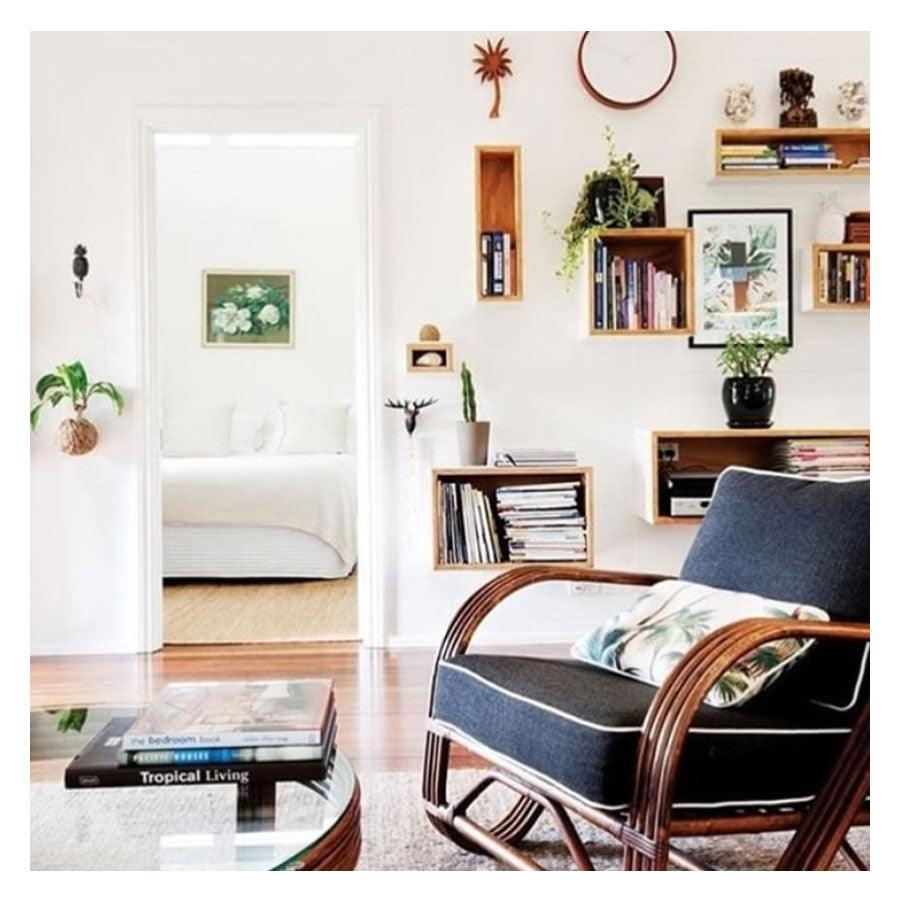 Cozy living room featuring a stylish chair, tropical decor, and a modern bookshelf for a serene home vibe.