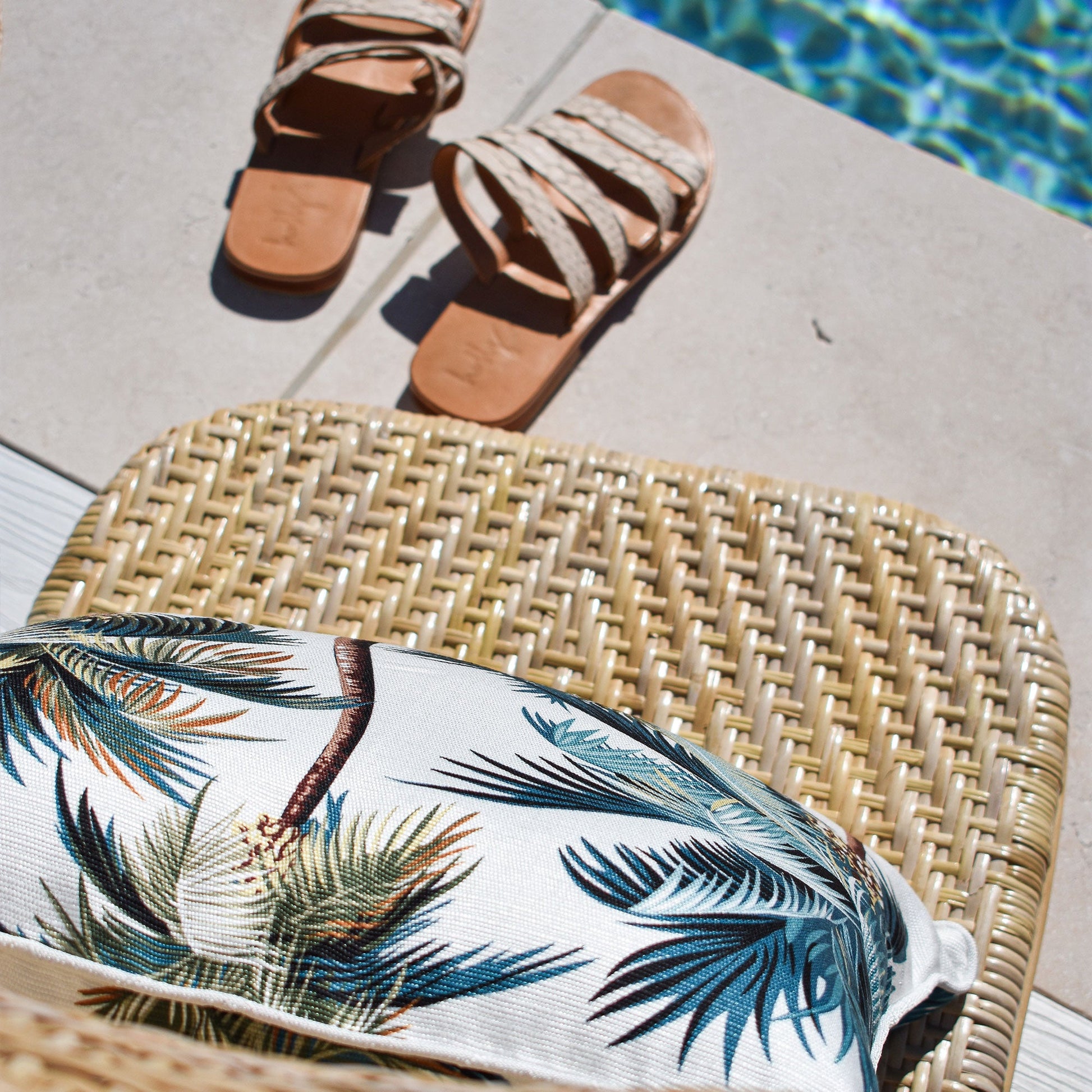 Cushion cover with palm trees on a chair by the pool, perfect for tropical indoor or outdoor decor.