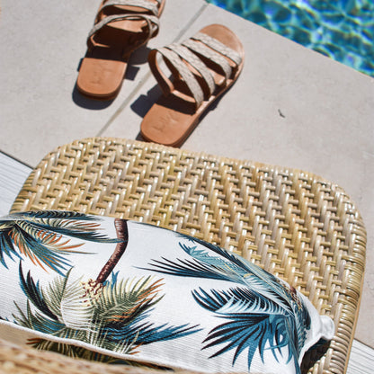 Cushion cover with palm trees on a chair by the pool, perfect for tropical indoor or outdoor decor.