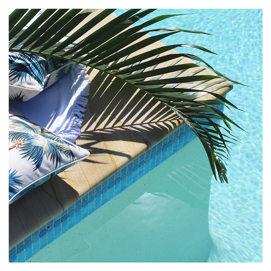 Tropical cushion cover by poolside with palm tree print, enhancing outdoor decor and relaxation.