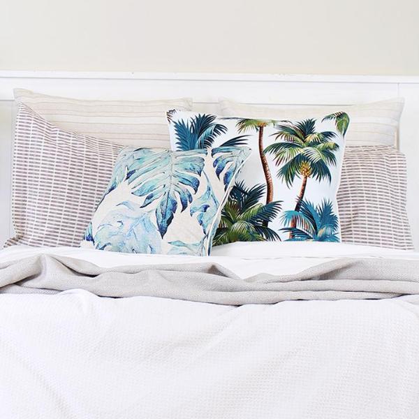 Cushion covers with tropical palm tree design on bed, adding a luxurious touch to home decor.