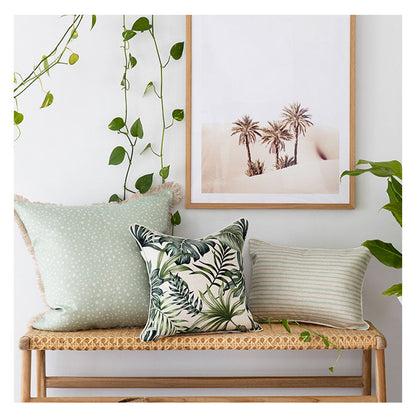 Vibrant cushion covers displayed on a bench in a tropical-inspired home setting, featuring greenery and beach-themed decor.