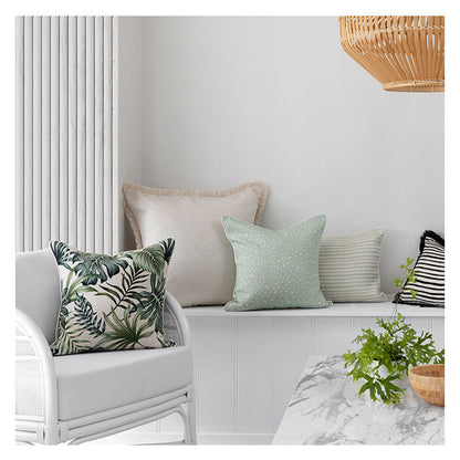 Stylish cushion covers in a tropical theme, enhancing a cozy indoor space with greenery and soft textures.