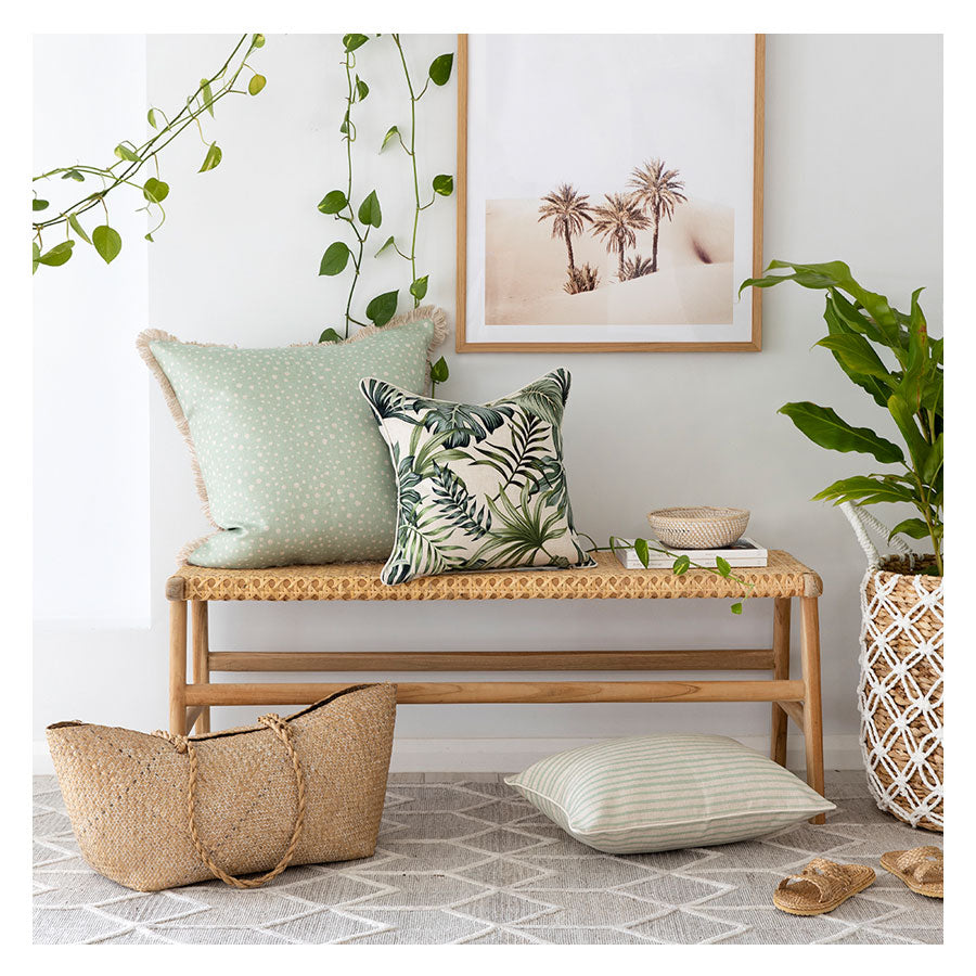 Tropical-inspired couch cushion covers displayed on a wooden bench with plants and decor, enhancing home aesthetics.