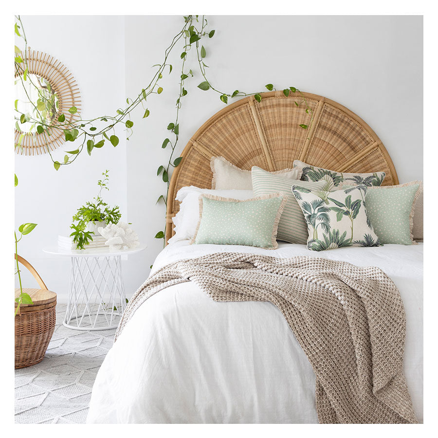 Stylish bedroom featuring tropical cushion covers, cozy blanket, and natural decor elements for a serene ambiance.