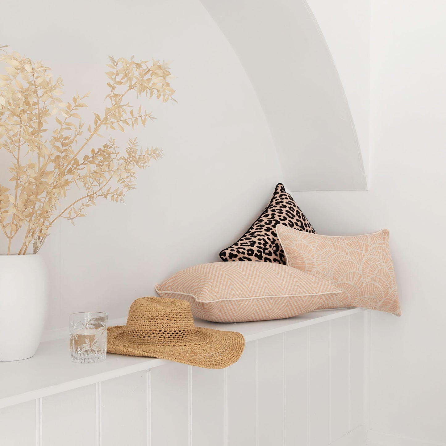 Stylish cushion covers in blush zigzag and leopard print, enhancing a cozy interior with natural decor elements.