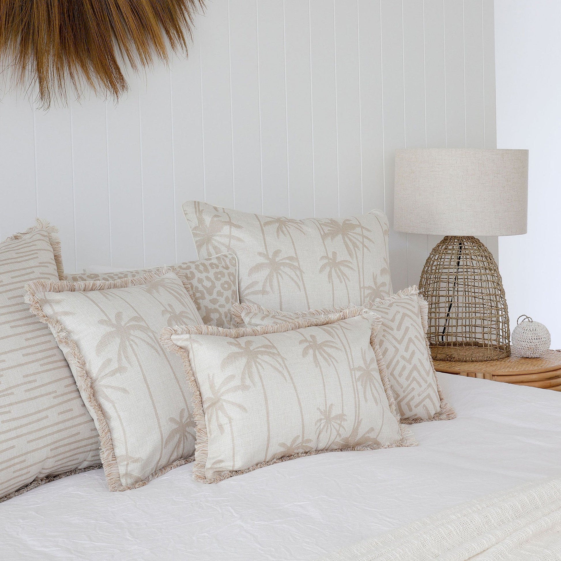 Elegant tropical-themed cushion covers on a stylish bed with a woven lamp, adding comfort and decor to any space.