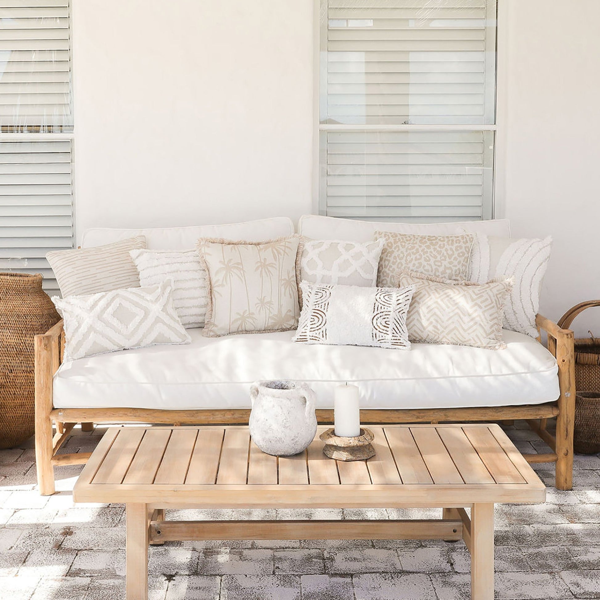 Cozy outdoor sofa with decorative cushion covers, featuring a mix of neutral tones and patterns, complemented by a wooden coffee table.