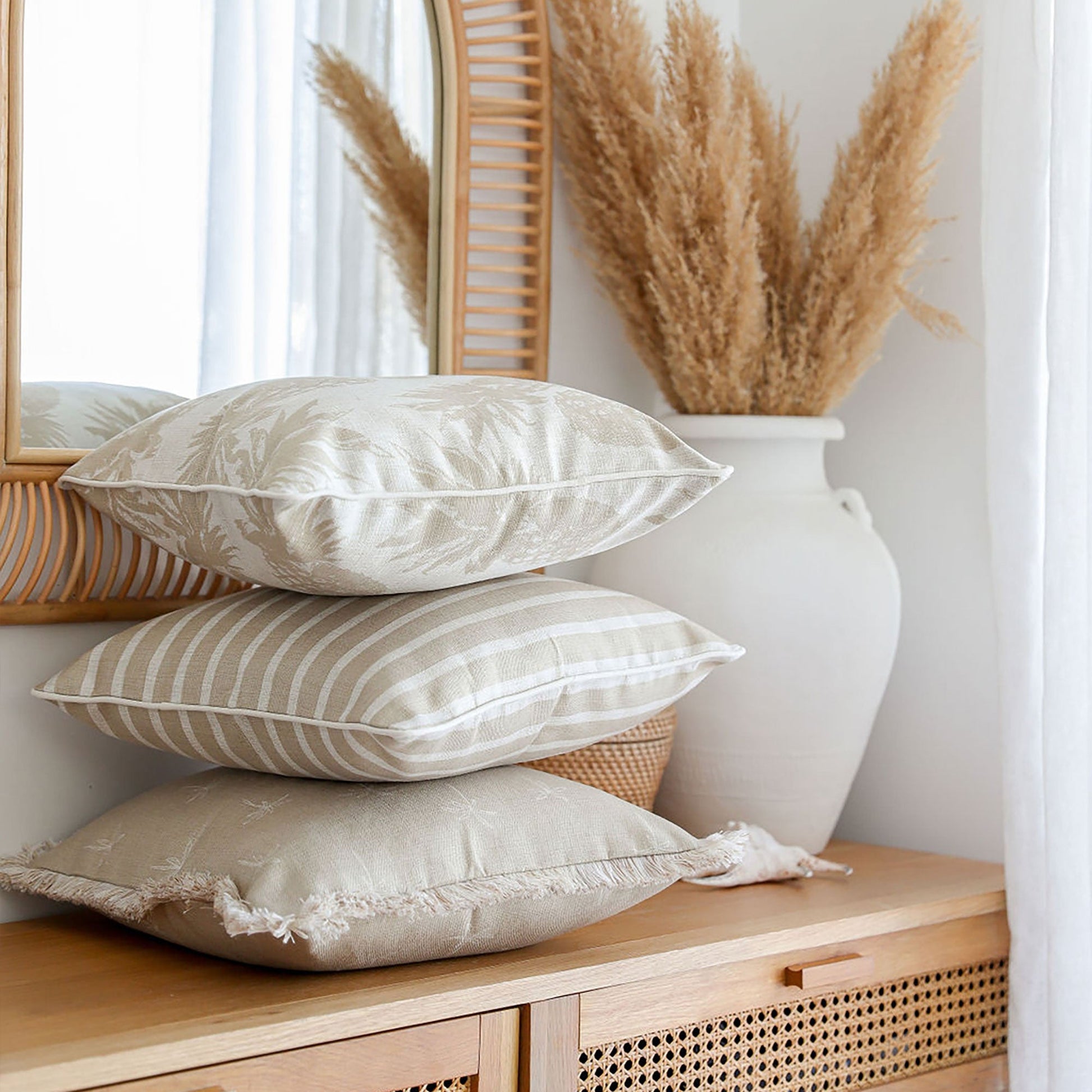 Beige cushion covers stacked on a wooden console table, enhancing a cozy, tropical home decor style.