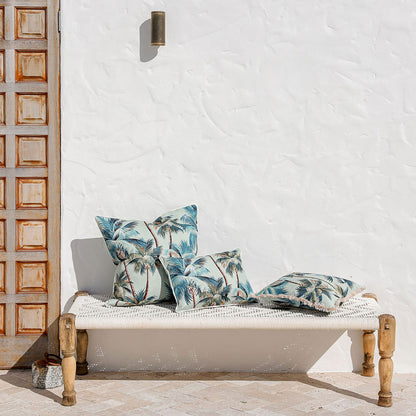 Tropical palm tree cushion covers on a stylish bench against a white wall, enhancing outdoor decor.