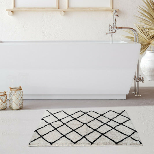 Soft cotton bath mat in tufted jacquard design beside a modern freestanding bathtub, enhancing bathroom aesthetics.