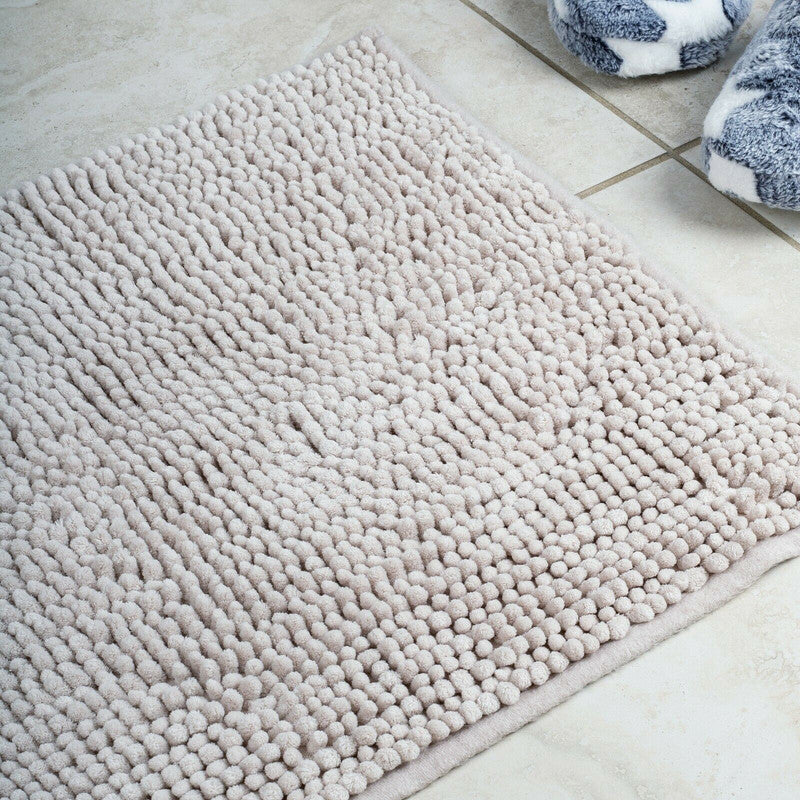 Soft pile light grey microfiber bath mat on tiled bathroom floor, providing a non-slip and cozy surface.