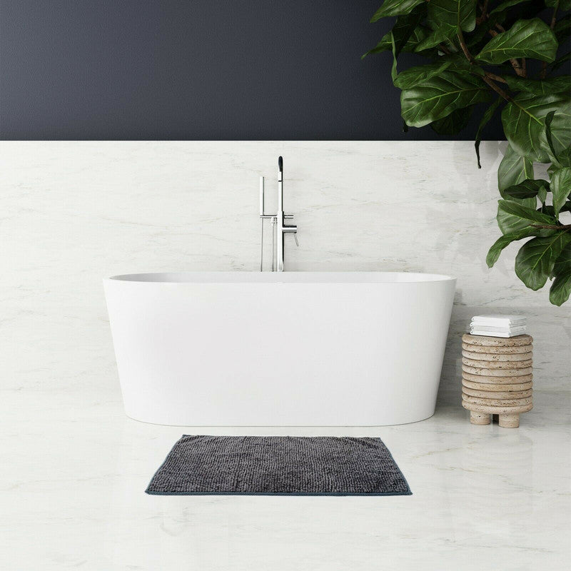 Microfiber bath mat in dark grey placed in modern bathroom with white tub and greenery for a stylish touch.