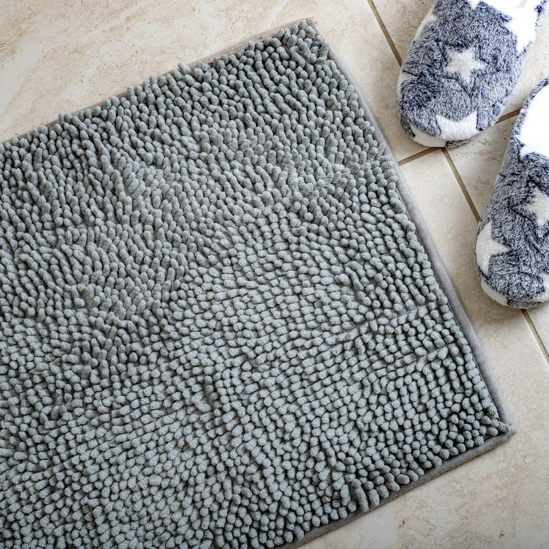 Soft gray microfiber bath mat with non-slip design beside cozy star-patterned slippers on a tiled floor.