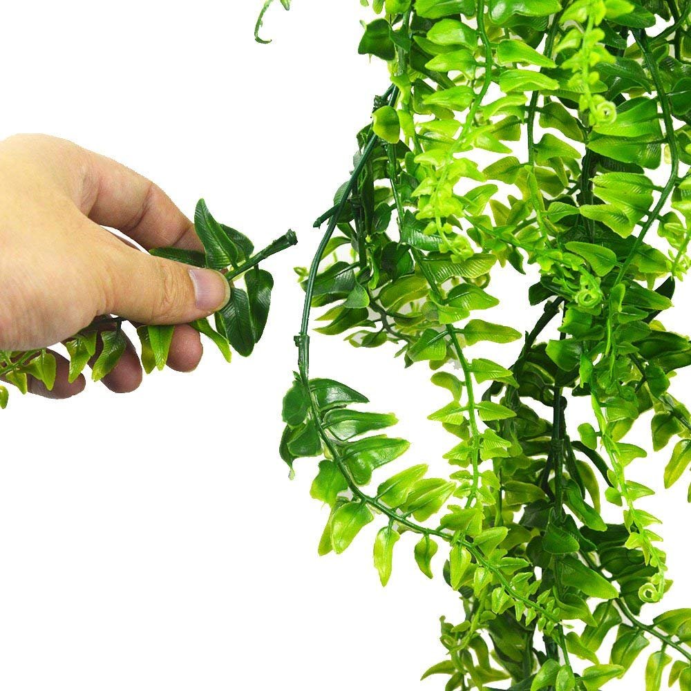 Hand holding a faux green vine, showcasing realistic artificial leaves for home and garden decoration.