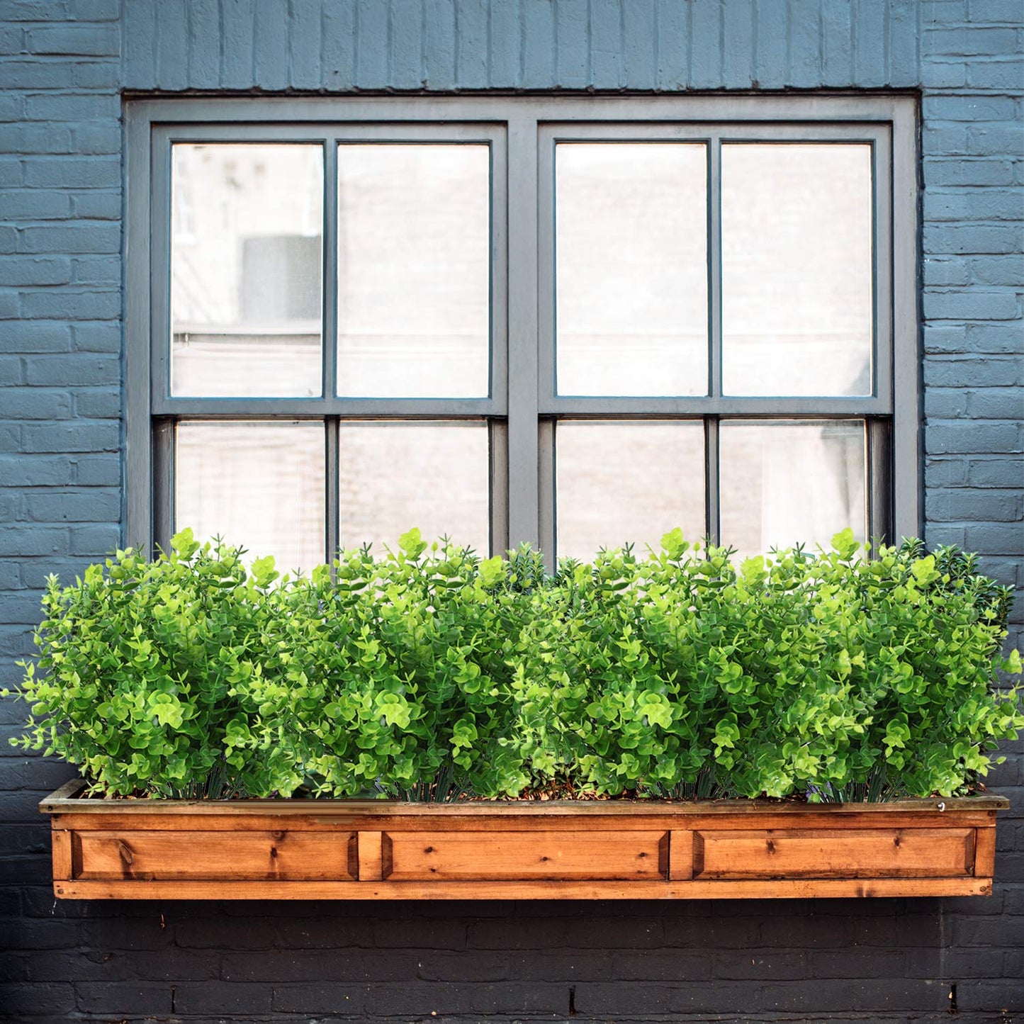 Artificial eucalyptus plants in a wooden window box adding vibrant greenery to a stylish urban setting.