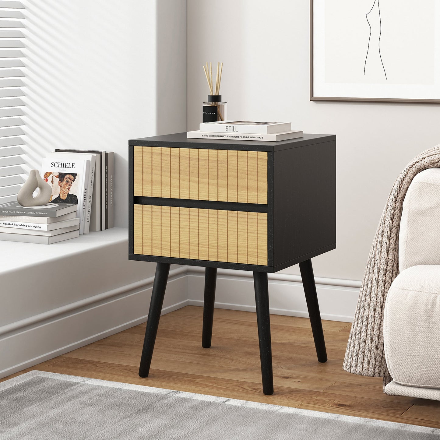 Black and natural Oslo bedside table with two drawers, solid pine wood legs, and melamine finish, placed in a modern bedroom.