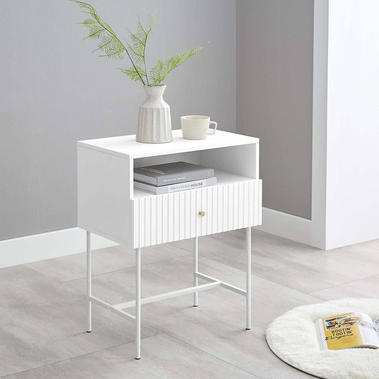 White Lucia bedside table with fluted design, featuring MDF body, metal legs, and shelf. Perfect for modern bedrooms.