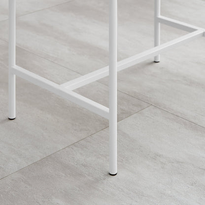 White metal legs of Lucia fluted bedside table in satin finish, shown on a gray tile floor. Perfect for modern bedroom decor.