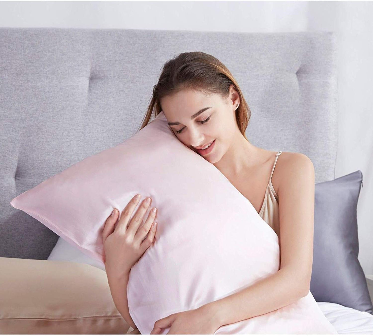 Woman enjoying the comfort of a luxury pink silk pillowcase for a restorative sleep experience.