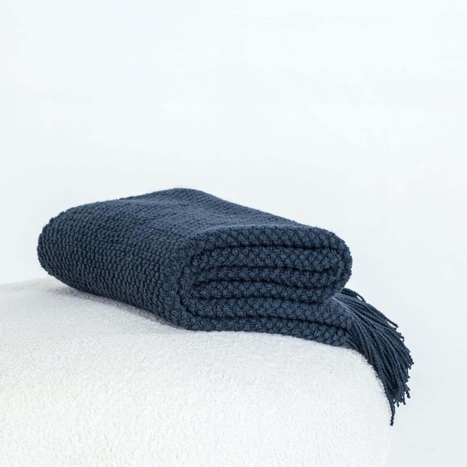 Navy micro plush knitted woven throw blanket displayed on a soft surface, ideal for adding warmth and elegance to any room.