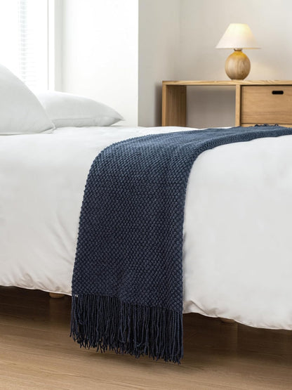 Navy Micro Plush Knitted Woven Throw Blanket elegantly draped over a bed, showcasing its premium acrylic fabric and cozy design.