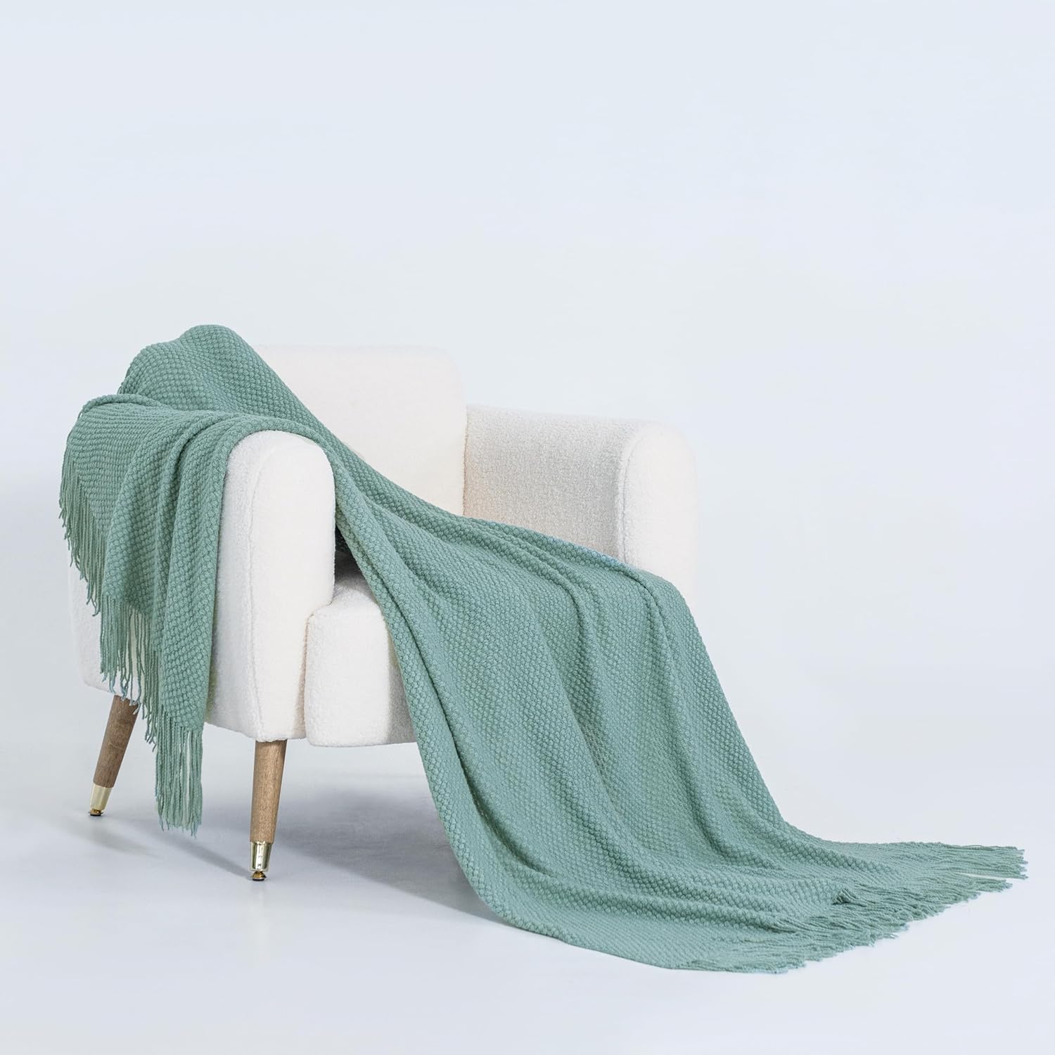 Seafoam micro plush throw blanket draped over a white armchair, showcasing its elegant woven design and cozy texture.