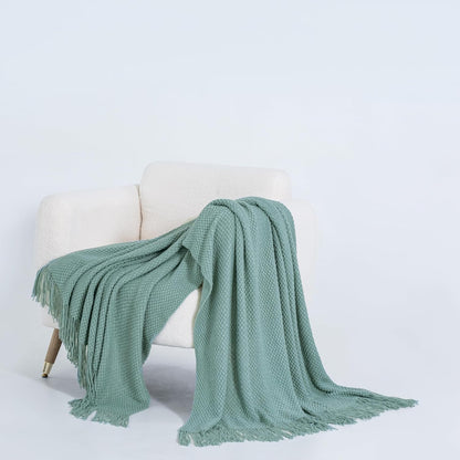 Seafoam micro plush knitted throw blanket draped over a cream chair, showcasing its luxurious texture and warmth. Perfect for couches and beds.