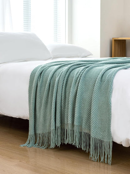 Seafoam micro plush knitted woven throw blanket draped over a bed, showcasing its softness and elegance. Perfect for couches and beds.