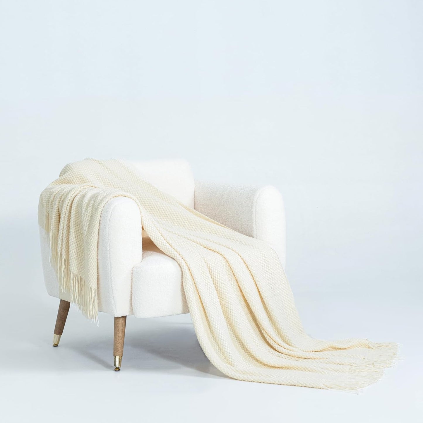 Snow-colored micro plush knitted throw blanket draped over white armchair, showcasing luxurious warmth and style.