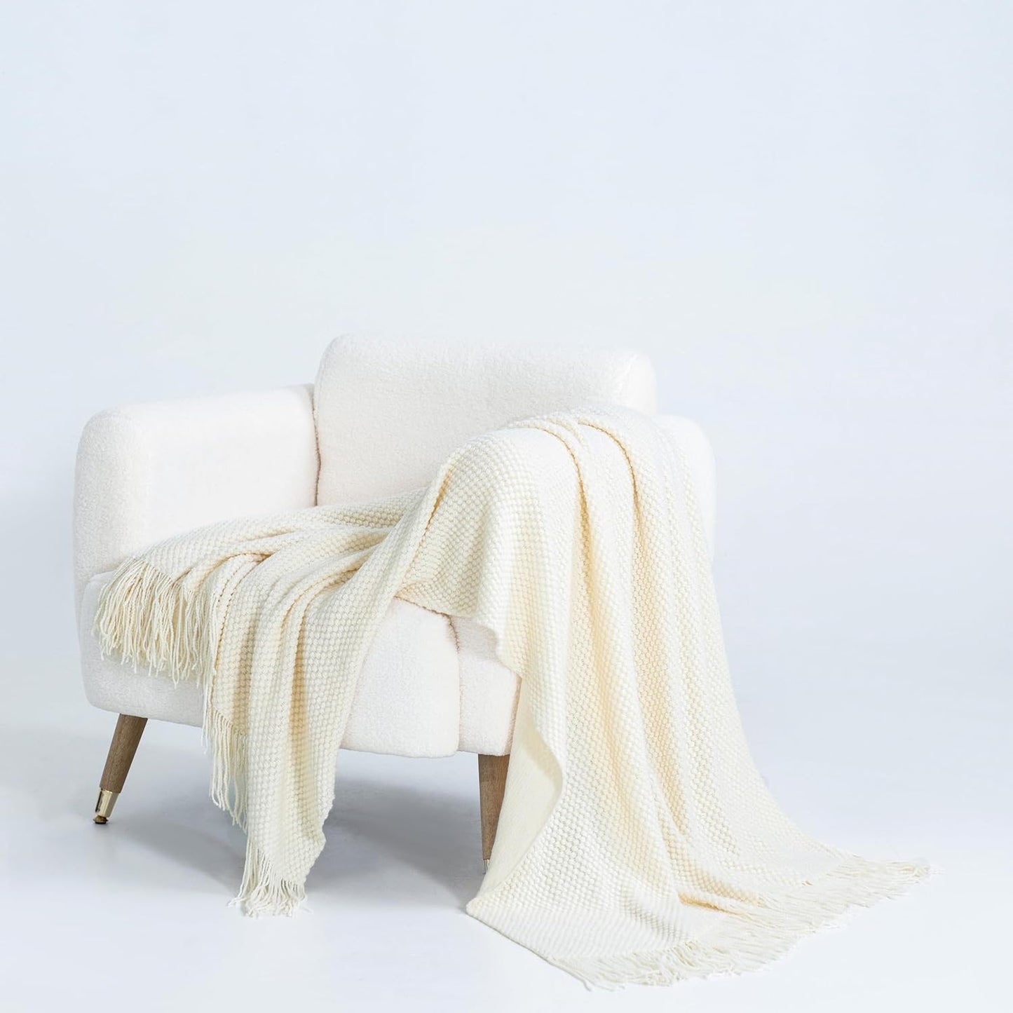 Cream micro plush knitted throw blanket draped over a white chair, showcasing cozy elegance and warmth in home decor.