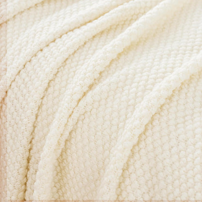 Snow-colored micro plush knitted woven throw blanket, close-up of textured acrylic fabric for cozy home decor throws and blankets.