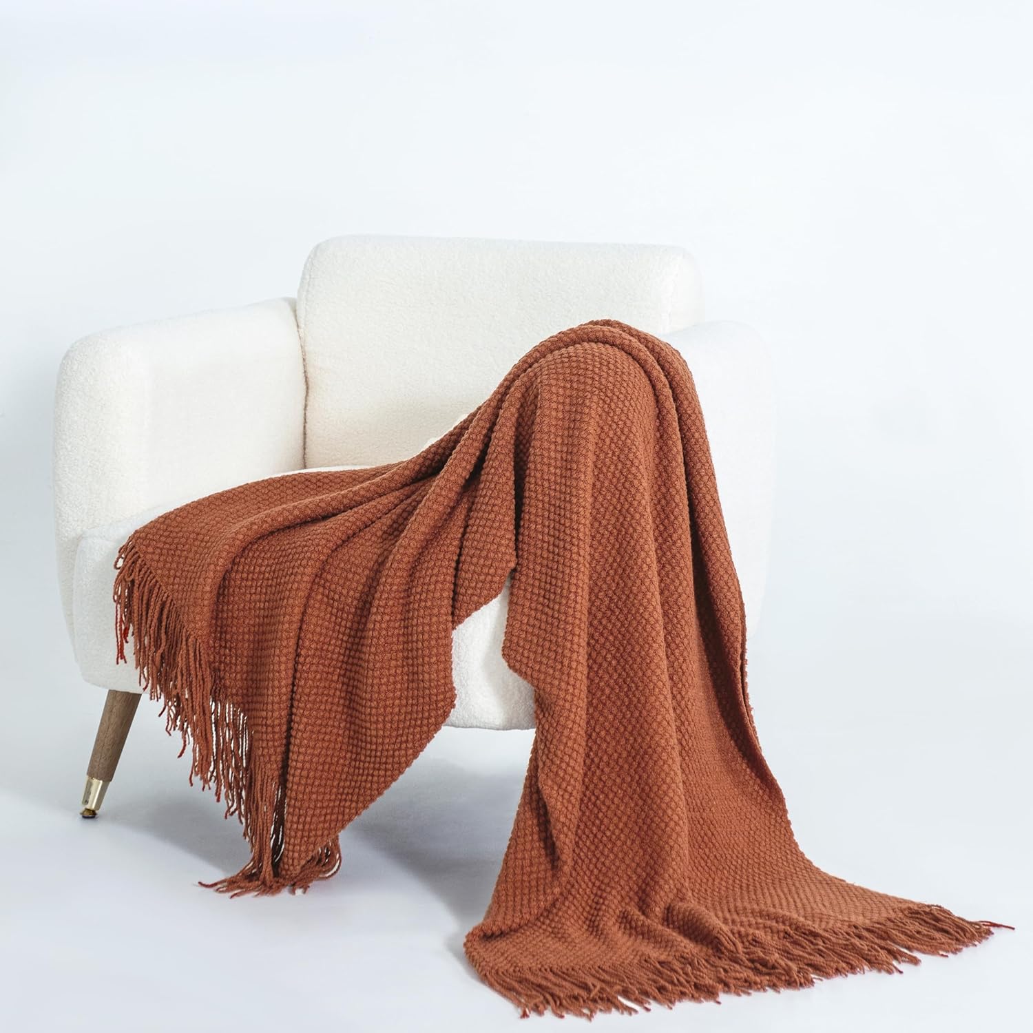 Terracotta knitted woven throw blanket on white chair, showcasing luxury, softness, and warmth. Ideal for sofas or beds, enhancing comfort.