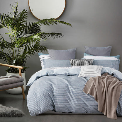 Cozy bedroom featuring Nathan 100% cotton reversible quilt cover set with striped design and stylish cushions.