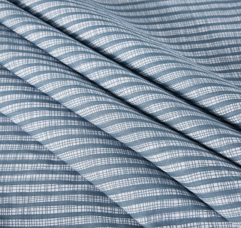 Close-up view of soft, textured cotton fabric featuring a blue and white grid pattern, ideal for quilt cover sets.