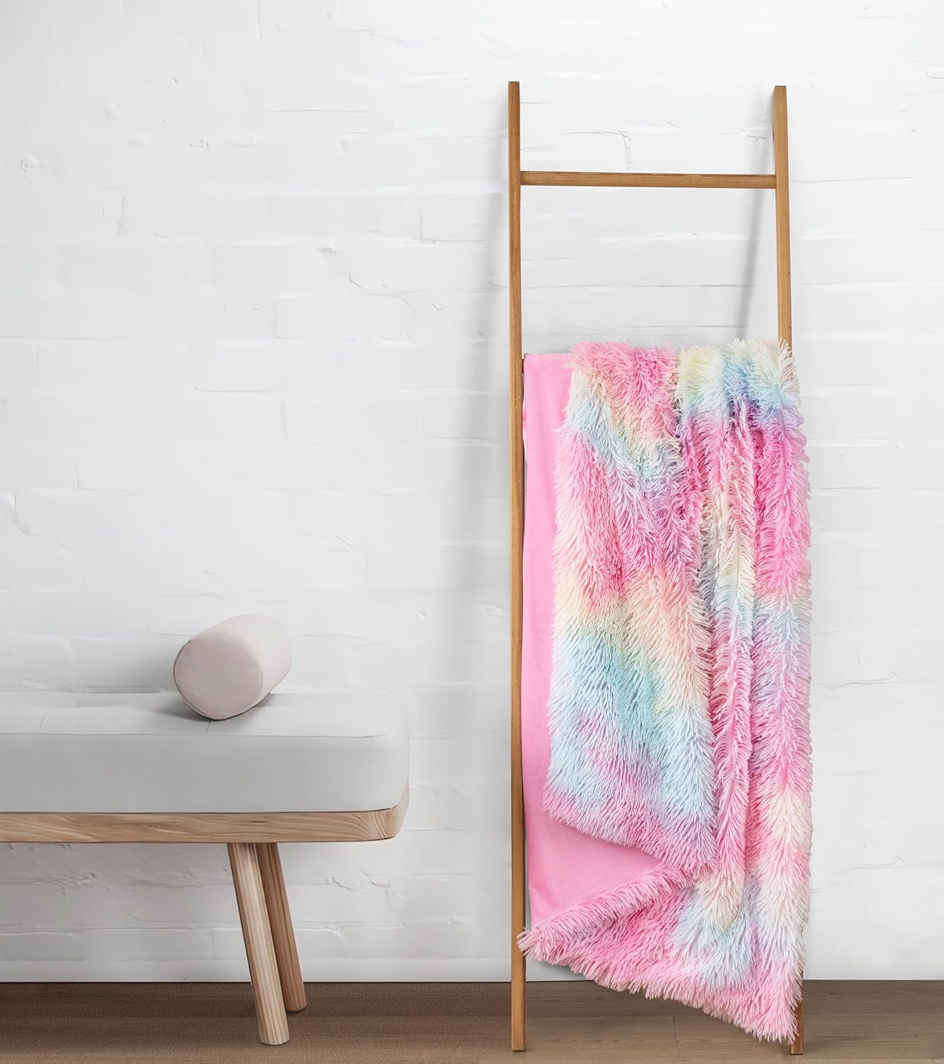 Rainbow faux fur throw blanket draped on a ladder, featuring plush shaggy texture and reversible microfiber velvet backing. Cozy home decor.