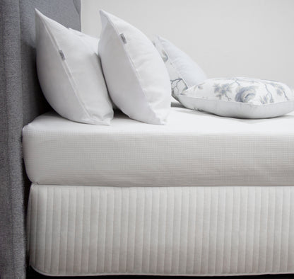 Elegant quilted white bed skirt with decorative pillows on a stylish king single bed. Perfect for modern bedroom décor.